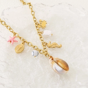 Vue détaillée du collier doré avec pendentifs en forme de coquillage, hippocampe et étoile