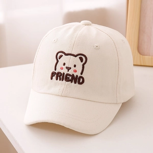 Dettaglio del ricamo dell'orso e della scritta 'FRIEND' sul cappellino in cotone beige