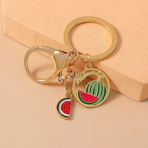 Detailed close-up of a golden watermelon keychain with enamel fruit charms and lobster clasp