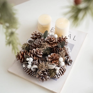 Nordic pine cone Christmas wreath with white berries and dried leaves on magazine