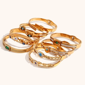 Detail of 18K gold-plated bracelets featuring evil eye motifs and green gemstones