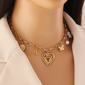 Détail du collier doré avec pendentifs de tournesol, papillon et perles délicates