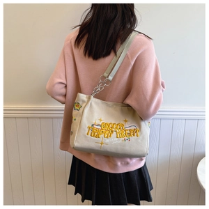 Detail of canvas tote bag featuring embroidered text and metal chain strap