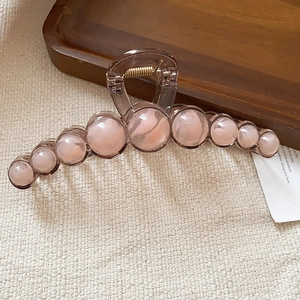 Detail of tortoiseshell resin hair claw with pink marble beads and gold metal spring