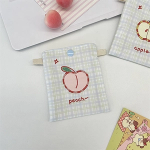 Close-up of checkered canvas pouch featuring peach embroidery and button closure