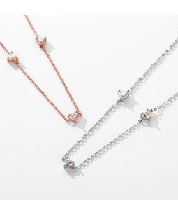 Macro shot of silver and rose gold necklaces featuring heart-shaped rainbow stones