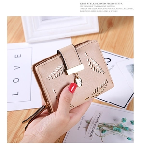 Close-up of a compact women wallet with hollow leaf design and gold leaf pendant charm