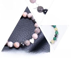 Detail view of natural stone bead bracelets with heart charms on elastic cord