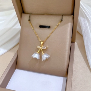Close-up of golden bell orchid necklace with white floral buds and sparkling crystals