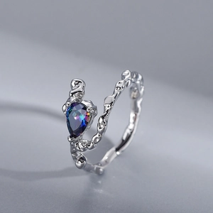 Irregular textured silver ring with a pear-cut iridescent gemstone on grey background