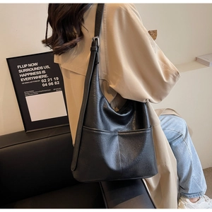 Detail of adjustable metal buckle and soft leather texture on a large black bucket bag