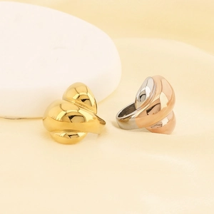 Close-up of polished 18k gold and silver sculptural croissant rings on a stone display