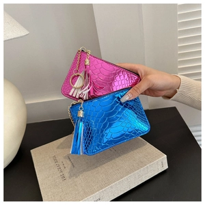 Close-up of crocodile pattern coin purses in fuchsia and blue with gold chain tassels
