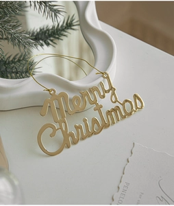 Macro shot of gold Merry Christmas hanging ornament with metallic mirror finish and golden string