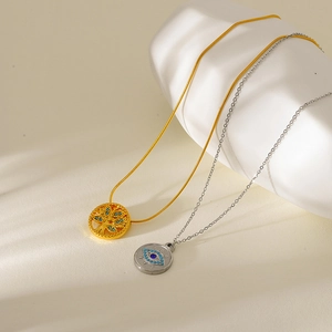 Close-up of gold tree of life and silver evil eye pendants on sleek snake chains