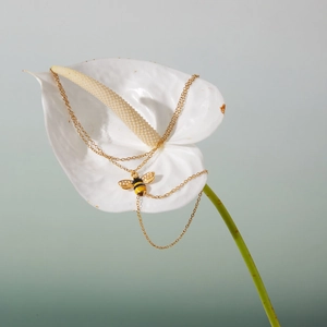 Makroaufnahme der goldenen Biene mit Emaille und Zirkon auf weißer Blume