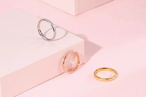 Three-color frosted stainless steel rings displayed on elegant pink geometric blocks