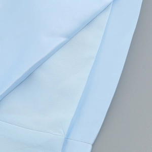 Detailed macro view of the light blue twill fabric texture and split hem stitching finish
