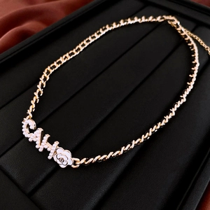 Macro shot of gold-plated chain with pearl accents and camellia charm detail