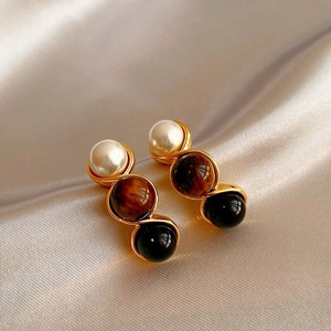 Close-up of vintage Maillard style earrings featuring tiger eye and pearl beads on silk