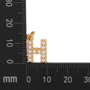 Detailed size measurement of a gold letter H pendant with pearls using a black ruler