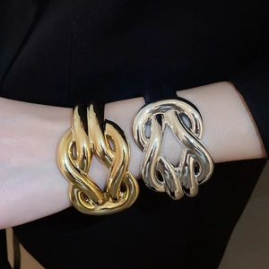 Detail of chunky knotted gold and silver acrylic bangles shown on model wrist