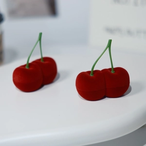 Detalle de joyeros de terciopelo con forma de cereza roja y tallos verdes