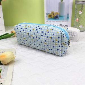 Detailed view of quilted cotton pen bag with blue and yellow plaid and dots on desk