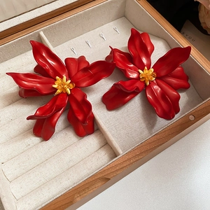 Detail of large red flower earrings with yellow beads in a wooden jewelry display box