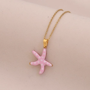 Detailed close-up of a pink starfish pendant with white polka dots on a gold chain