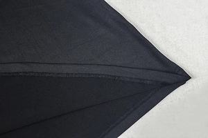 Detailed close-up showing precision stitching and hem finish on black knitted dress