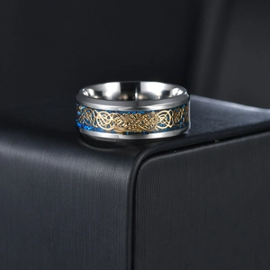 Macro detail of silver titanium ring featuring gold dragon inlay on a blue galaxy background