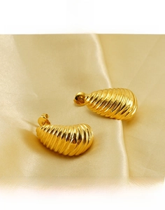 Detailed macro view of gold-plated titanium steel earrings with spiral ribbed texture