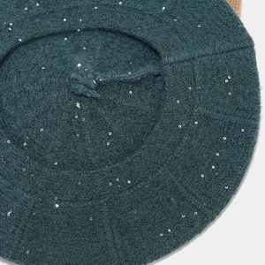 Detail of dark green sequined knit beret showing thick wool texture and silver sparkles
