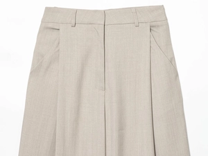 Detail of high-waisted gray trousers showing pleated design and woven fabric texture