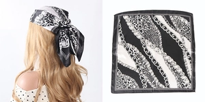 Macro detail of high-quality black and white satin scarf with leopard and chain pattern print