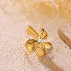 Retro gold flower ring with pearl center on beige background in high quality setting