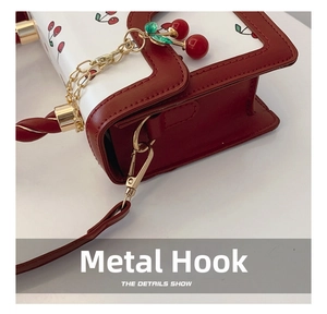Detail of cute cherry print bag with gold metal hook and decorative cherry pendant