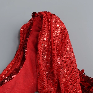 Gros plan des paillettes rouges et du tissu mesh sur une robe de Noël licou sexy