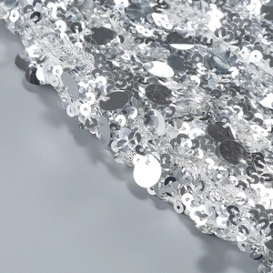 Detailed macro view of dense silver sequins on mesh fabric for elegant evening dresses