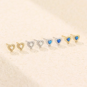 Macro view of heart-shaped opal earrings with zircon halo in gold and silver finishes