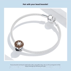 Macro detail of silver mesh bracelet with Forever Love clasp and snowflake pendant