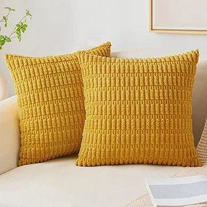 Close-up of two yellow corduroy pillow covers with textured pattern on a beige sofa