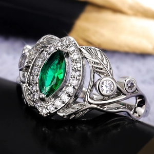 Macro shot of marquise-cut green gemstone ring with leaf-shaped hollow metal carving