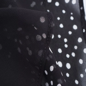 Macro view of black polka dot chiffon fabric with delicate stitching and sheer texture