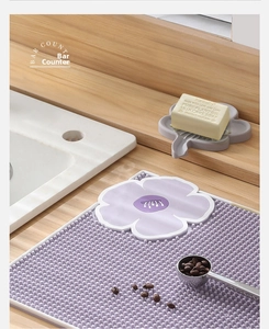 Detail of purple silicone soap dish with drainage mat and floral soap holder on counter