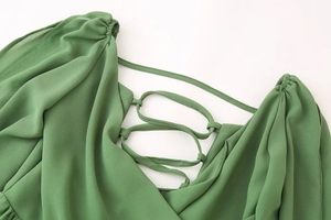 Détail d'une robe verte avec un design dos nu à lacets complexe sur tissu léger