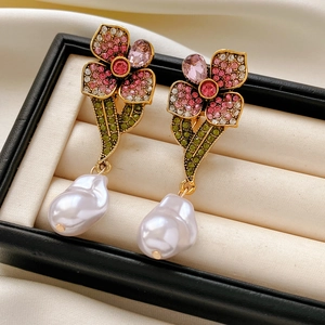 Vue macro de boucles d'oreilles fleur vintage avec strass colorés et perles baroques