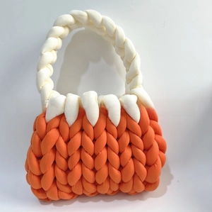 Detailed macro view of handmade chunky knit handbag with orange and white woven textures