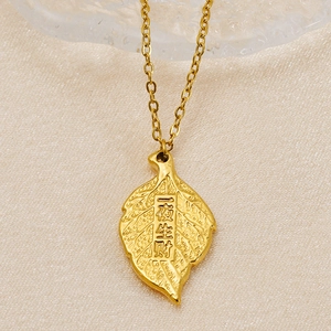 Minimalist gold leaf pendant necklace with Good Fortune engraving on silk background